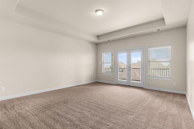 carpeted spare room with visible vents, french doors, baseboards, and a tray ceiling