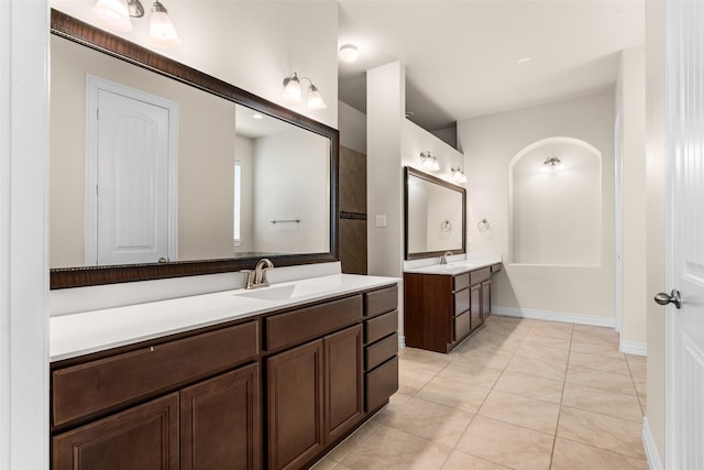 full bathroom featuring tile patterned floors, two vanities, baseboards, and a sink