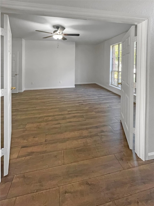 unfurnished room with ceiling fan and dark wood-type flooring