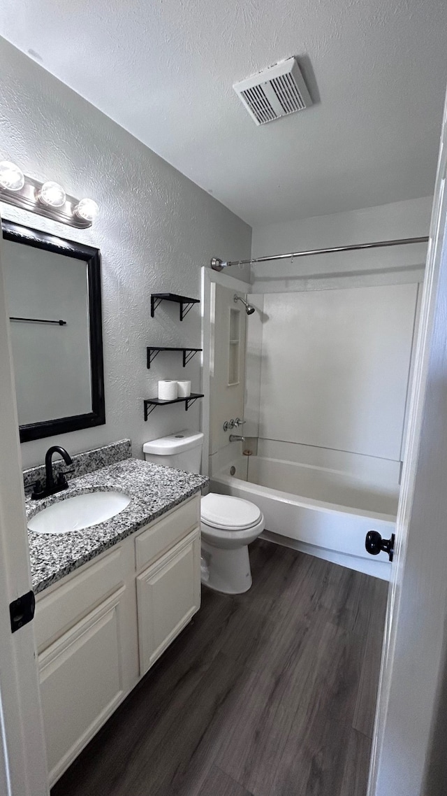 full bathroom featuring shower / tub combination, hardwood / wood-style floors, toilet, vanity, and a textured ceiling