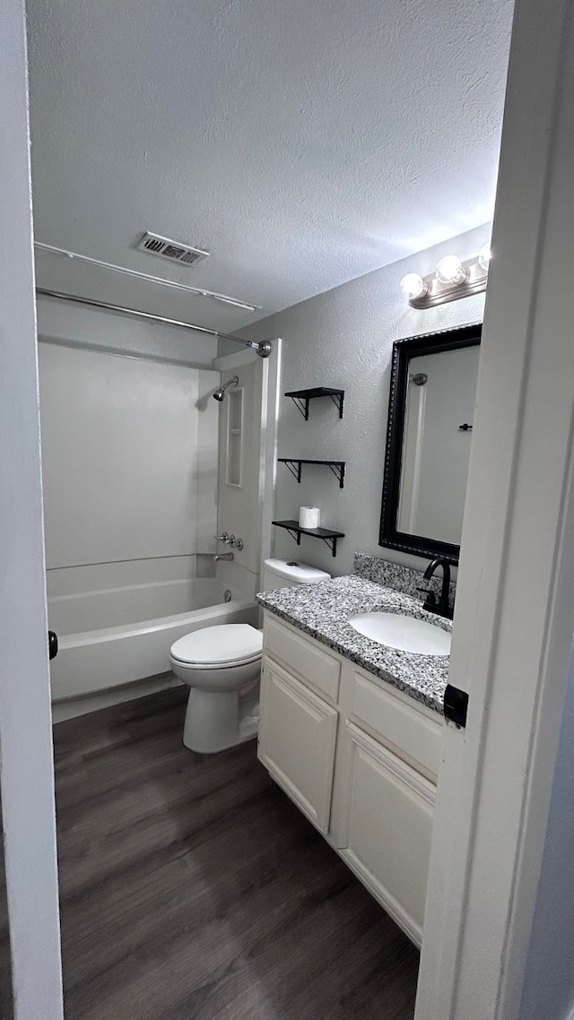 full bathroom featuring toilet, hardwood / wood-style flooring,  shower combination, and vanity