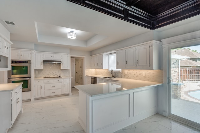 kitchen featuring a wealth of natural light, stainless steel appliances, kitchen peninsula, and white cabinetry