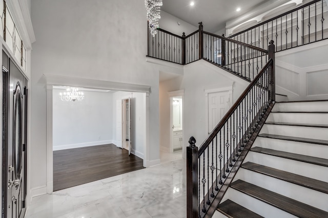 entrance foyer featuring light hardwood / wood-style floors, an inviting chandelier, and a towering ceiling