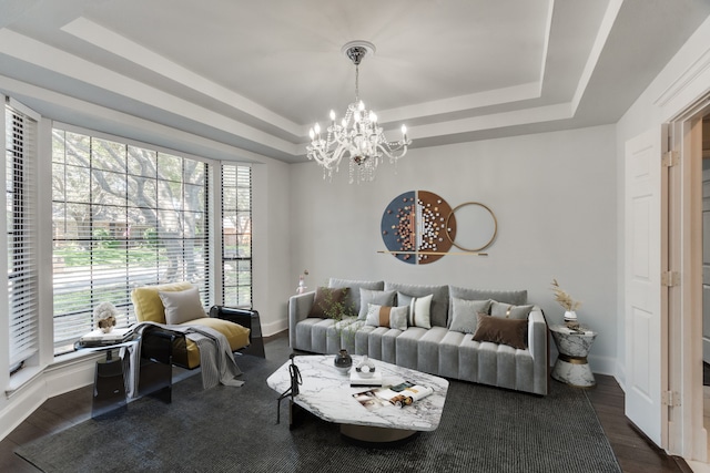 living room with a raised ceiling, dark hardwood / wood-style flooring, and a chandelier