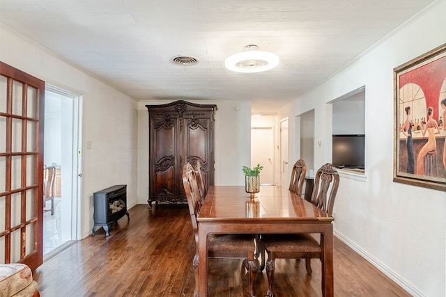 dining room featuring plenty of natural light, a wood stove, dark hardwood / wood-style flooring, and ornamental molding