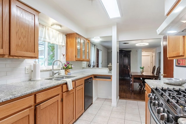 kitchen with high end stainless steel range, light stone countertops, sink, black dishwasher, and exhaust hood