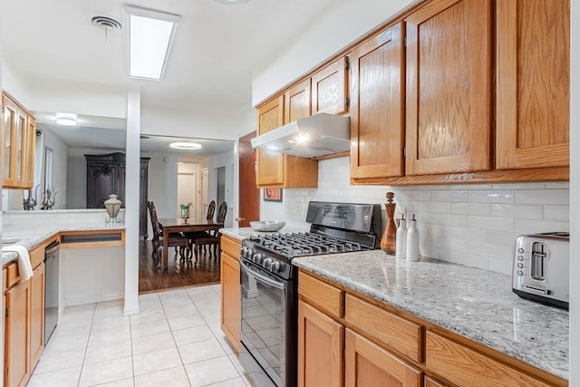 kitchen featuring light stone countertops, dishwasher, light tile patterned floors, backsplash, and black range with gas stovetop