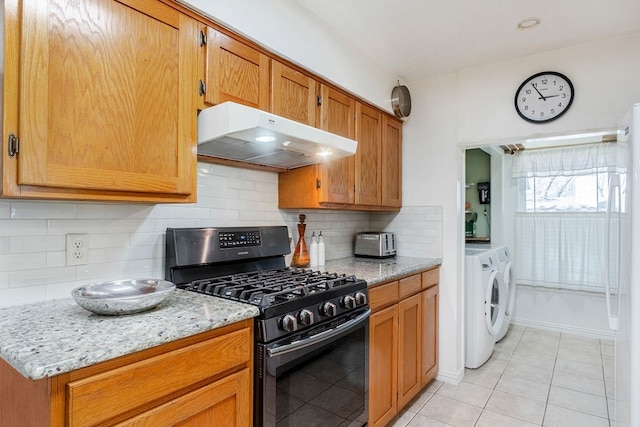 kitchen with backsplash, light tile patterned floors, gas stove, light stone counters, and washer and clothes dryer