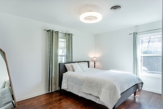 bedroom with dark hardwood / wood-style flooring and multiple windows