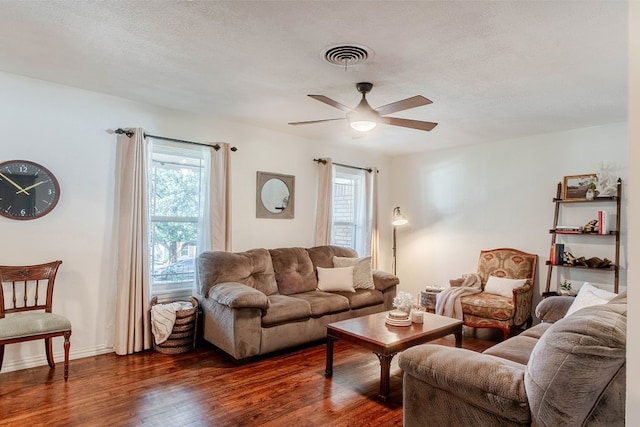 living room with a textured ceiling, ceiling fan, and dark hardwood / wood-style flooring