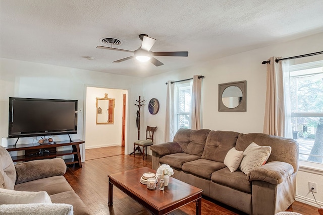 living room featuring ceiling fan, dark hardwood / wood-style floors, and a textured ceiling