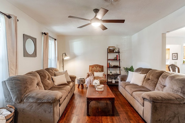 living room with a textured ceiling, ceiling fan, and dark hardwood / wood-style floors