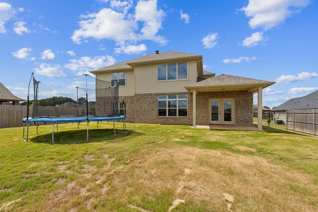 back of property with a trampoline, a yard, and a patio