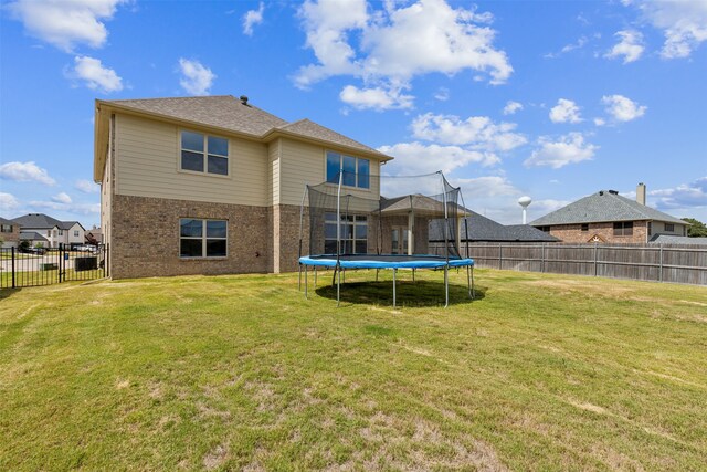 rear view of house featuring a yard and a trampoline