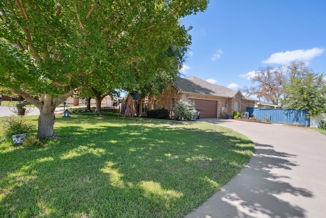 view of property hidden behind natural elements with a garage and a front yard