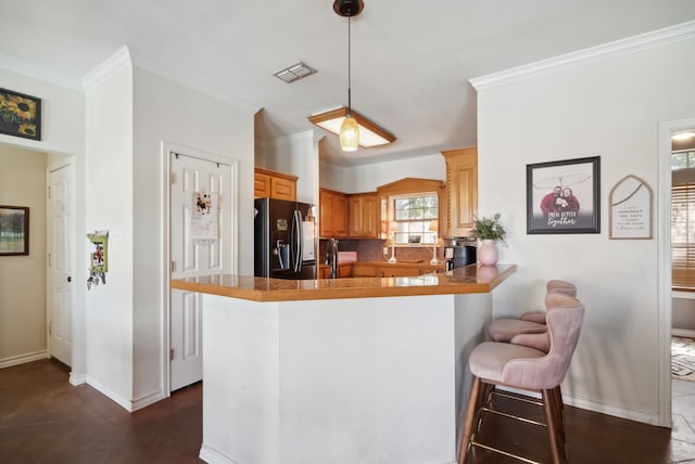 kitchen featuring kitchen peninsula, stainless steel fridge, a breakfast bar, and crown molding