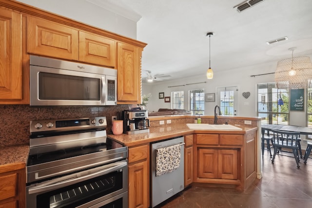 kitchen with backsplash, sink, dark tile patterned floors, appliances with stainless steel finishes, and kitchen peninsula