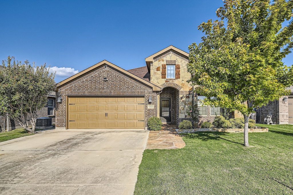 view of front of house featuring a front lawn, central air condition unit, and a garage