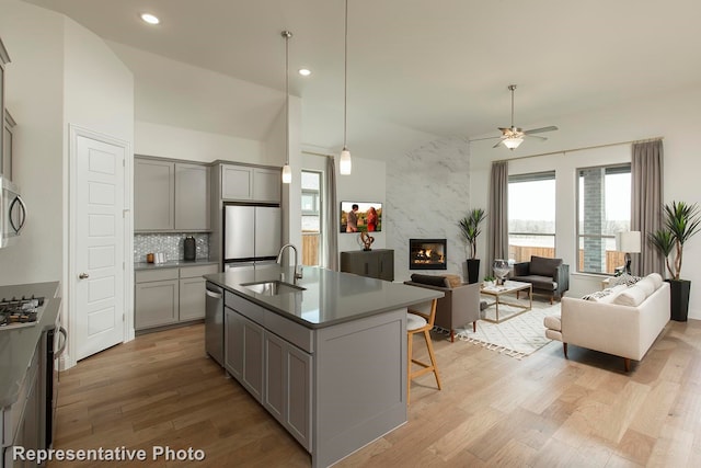 kitchen featuring gray cabinetry, stainless steel appliances, a high end fireplace, and ceiling fan