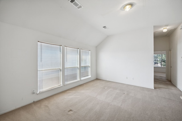 empty room featuring vaulted ceiling and light carpet