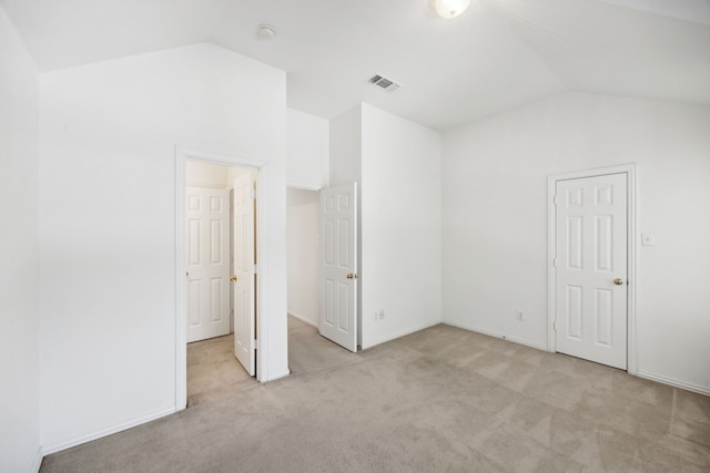 unfurnished bedroom with light colored carpet, vaulted ceiling, and a closet