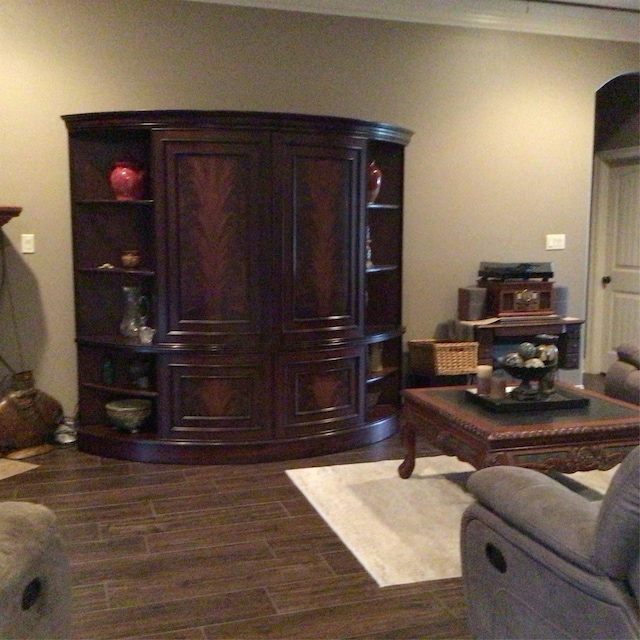 living room featuring dark wood-type flooring and crown molding