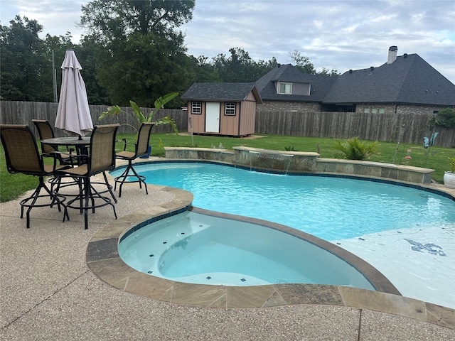 view of swimming pool featuring a yard, pool water feature, a storage unit, and a patio area