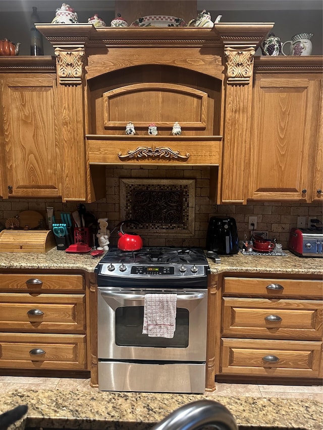 kitchen featuring stainless steel range oven, tasteful backsplash, and light stone counters