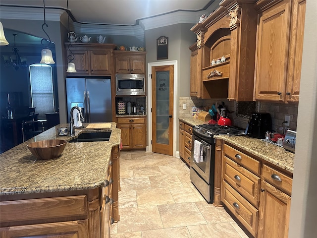 kitchen with stainless steel appliances, an island with sink, pendant lighting, sink, and backsplash