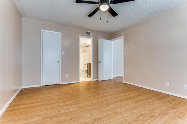 unfurnished bedroom with visible vents, light wood-style flooring, a textured ceiling, ensuite bath, and baseboards