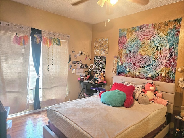 bedroom with a textured ceiling, ceiling fan, and wood-type flooring