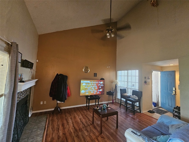 living room with a tiled fireplace, high vaulted ceiling, dark hardwood / wood-style floors, and ceiling fan