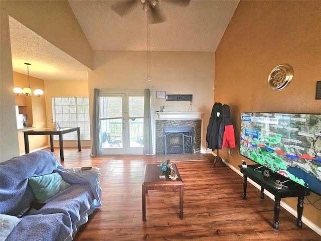 living room featuring ceiling fan, a stone fireplace, high vaulted ceiling, and hardwood / wood-style flooring