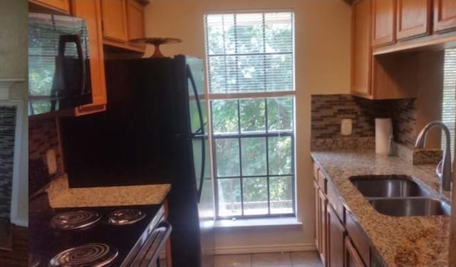 kitchen with a wealth of natural light, sink, and light stone countertops