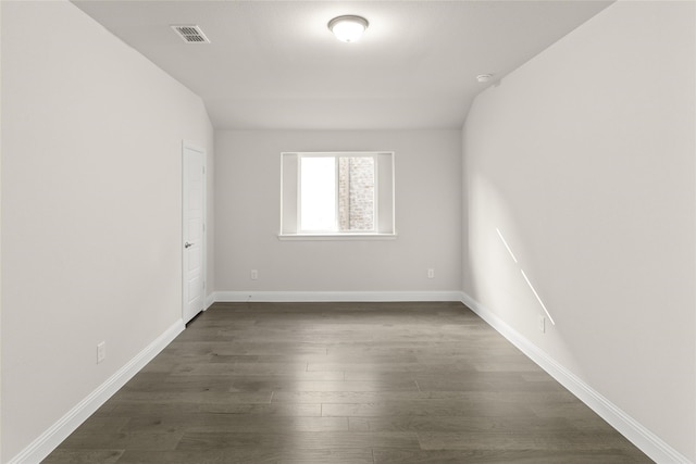 empty room featuring vaulted ceiling and dark wood-type flooring