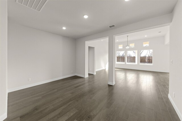 unfurnished living room featuring ceiling fan, a tile fireplace, dark hardwood / wood-style flooring, and a towering ceiling