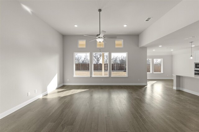 unfurnished living room featuring ceiling fan, a tile fireplace, and dark hardwood / wood-style flooring