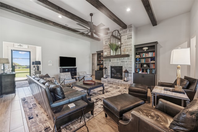 tiled living area with beam ceiling, a fireplace, and a ceiling fan