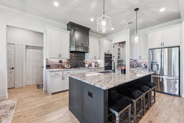 kitchen with light wood finished floors, visible vents, crown molding, appliances with stainless steel finishes, and a sink