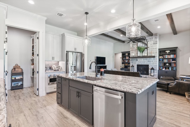 kitchen with visible vents, a sink, open floor plan, white cabinetry, and appliances with stainless steel finishes