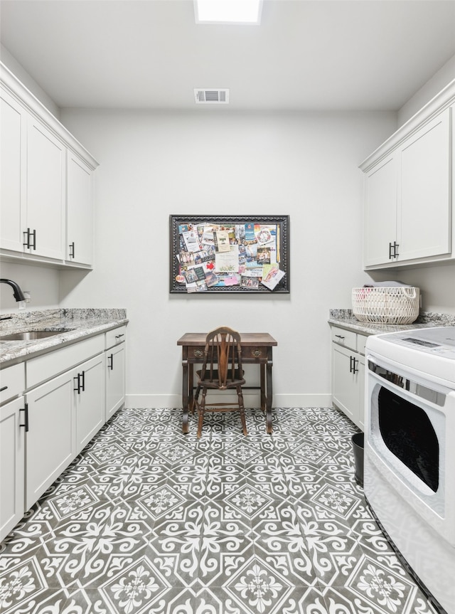 washroom with visible vents, cabinet space, baseboards, and a sink