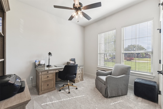 carpeted office space featuring baseboards and ceiling fan