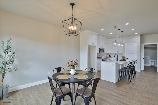 dining area featuring an inviting chandelier, light hardwood / wood-style flooring, and sink