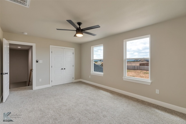 unfurnished bedroom featuring multiple windows, ceiling fan, and carpet