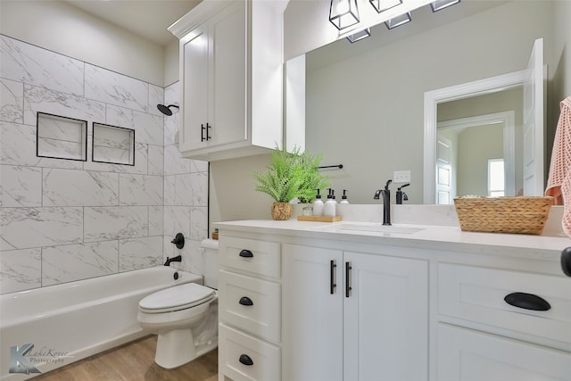 full bathroom with vanity, toilet, hardwood / wood-style floors, and tiled shower / bath