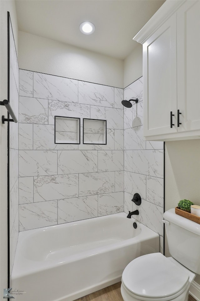 bathroom featuring toilet, hardwood / wood-style floors, and tiled shower / bath