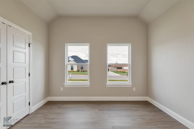 empty room with lofted ceiling and light hardwood / wood-style floors