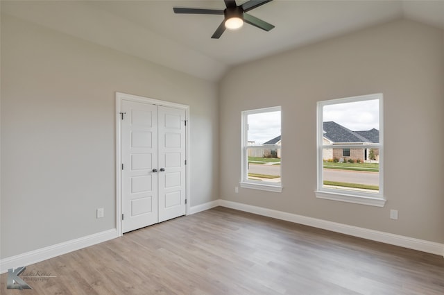 unfurnished bedroom with lofted ceiling, light hardwood / wood-style flooring, ceiling fan, and a closet