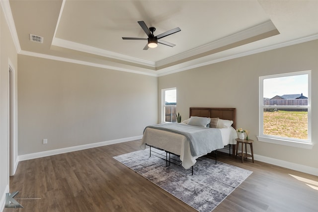 bedroom with a tray ceiling, multiple windows, ceiling fan, and dark hardwood / wood-style floors