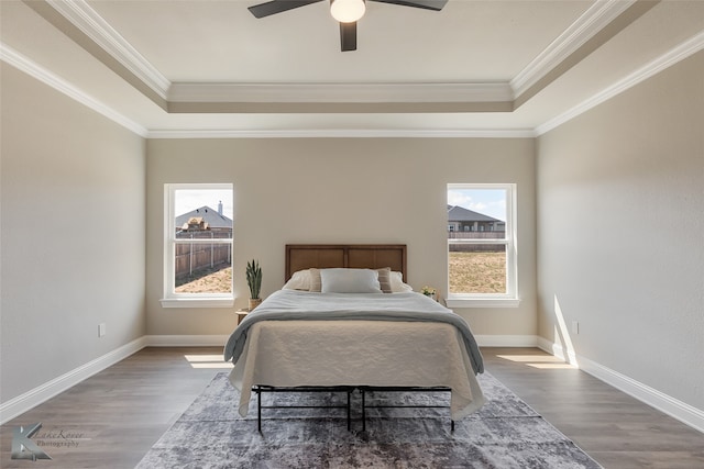 bedroom featuring multiple windows, ceiling fan, wood-type flooring, and ornamental molding